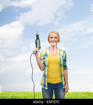 lächelnde Frau mit Bohrmaschine Stockfoto