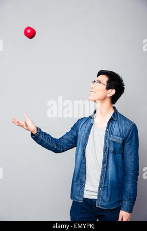 Glücklicher Junge asiatische Mann mit roter Apfel auf grauem Hintergrund Stockfoto