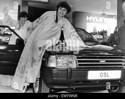 Tracey Woodland 18, links von Studley und Julie Greatorex 21 aus Solihull gesehen hier gekleideten in koreanischen Tracht auf dem Hyundai-Stand mit der Hyundai-Stella-1600 GSL auf der Motor Show 1984, 16. Oktober 1984 darstellen Stockfoto