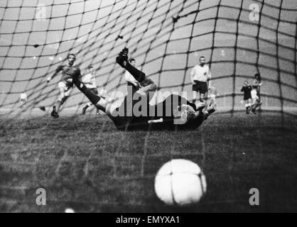 Manchester United gegen HJK Helsinki. HJK Keeper taucht und verfehlt den Ball, wie Denis Law während Uniteds 6: 0-Sieg über Helsinki in den Europapokal der Landesmeister blickt auf. 6. Oktober 1965 Stockfoto