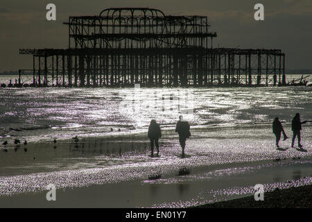 Wanderer machen Sie einen Abendspaziergang entlang der Strand von Brighton, mit den Resten der zerstörten West Pier im Hintergrund Stockfoto