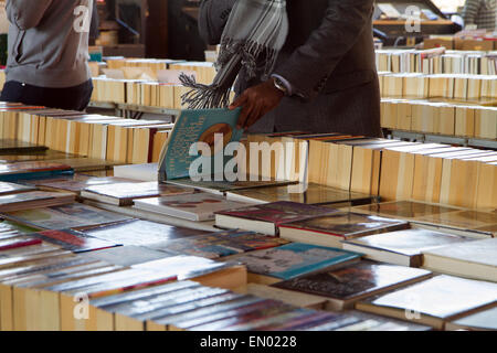 Ein Mann blättert Bücher zum Verkauf auf dem Markt an Londons South Bank Stockfoto