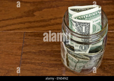 Dollar-Scheine in Mason Glas auf Holz. Stockfoto