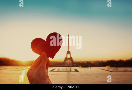 schöne Vintage-Karte von Paris, Eiffelturm und Hand mit Papierherz bei Sonnenaufgang Stockfoto