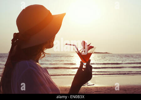 Frau mit Cocktail bei Sonnenuntergang Strand Stockfoto