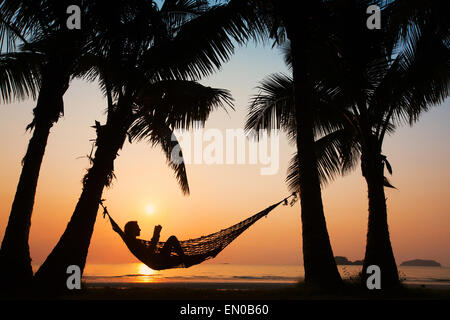Strandurlaub, Silhouette der Frau in Hängematte liest Stockfoto