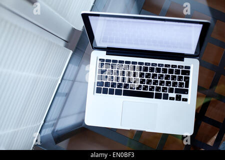Draufsicht der Laptop auf Glastisch im modernen Interieur Stockfoto