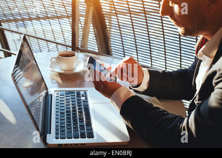 Business-Mann über Internet auf Smartphone und laptop Stockfoto