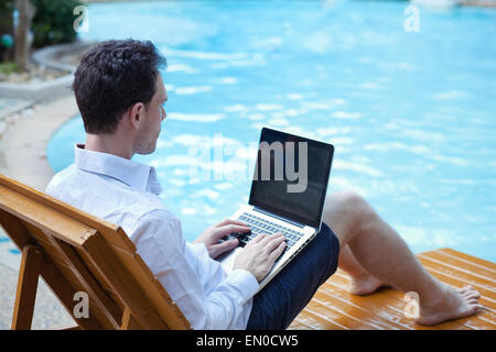 Business-Mann mit Laptop im Luxus-Hotel in der Nähe von Schwimmbad Stockfoto