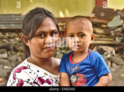 Eine junge indonesische Mutter hält ihr Sohn durch den Hafen auf der Insel Tagulandang, Siau, Nord Sulawesi, Indonesien Stockfoto