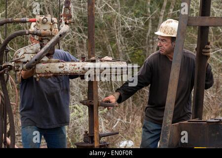 Ölarbeiter Waschbecken Rohre mit Hilfe einer Derrick für Rohöl in Evangeline, Louisiana zu bohren. Die Ölfelder wurden die ersten Brunnen in Louisiana. Stockfoto