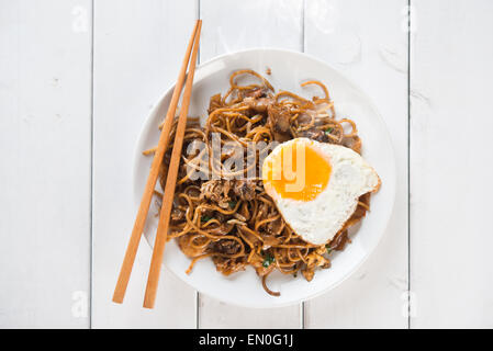 Gebratenes Char Kuey Teow mit Garnelen und Ess-Stäbchen aus Holz Hintergrund. Stockfoto