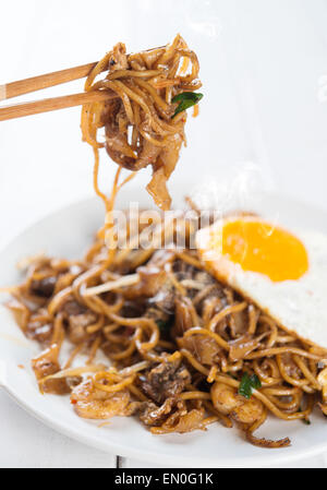 Close-up rühren gebraten Saibling Kuey Teow auf Ess-Stäbchen über hölzerne Hintergrund. Stockfoto