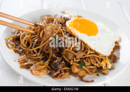 Close-up rühren gebraten Saibling Kuey Teow mit Ess-Stäbchen über hölzerne Hintergrund. Stockfoto