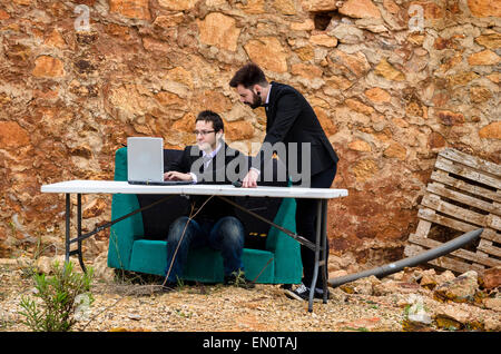 Zwei Jungs um einen Schreibtisch in einem Grunge-Büro, ein Konkurs-Konzept Stockfoto