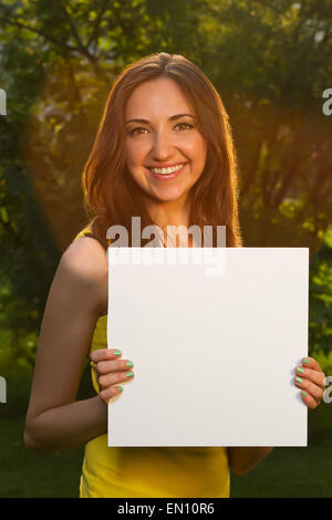 Glücklich lächelnd junges Mädchen mit weißen Blankopapier gegen backg Stockfoto