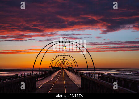 Southport, Merseyside, England 25. April 2015 UK Wetter. Farbenfrohen Sonnenuntergang über Southport Attraktionen. Zu dieser Zeit des Jahres richtet sich die untergehende Sonne direkt entlang der Länge des Piers, ein lokaler saisonale Stonehenge Art auftreten, mit dem Jahrgang viktorianischen Pier, die scheinbar bis zum Horizont erstrecken, wie die Sonne über die irische See. Bildnachweis: Mar Photographics/Alamy Live-Nachrichten Stockfoto