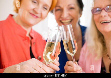 Drei Lächeln Mama Freunde werfen Gläser Champagner feiern ihre Freundschaft. In Makro aufgezeichnet. Stockfoto