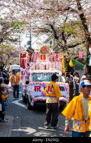 Stewards, die den Weg für Kirsch blssom dekoriert van in der jährlichen Genji Parade in der engen Straße bei Tada, Japan, unter den Kirschblüten. Stockfoto