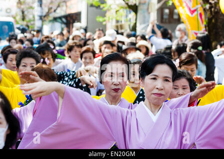 Ein Team reifer Frauen in Kimono-Kleidung singt und tanzt unter den Kirschblüten während der jährlichen Genji-Parade im Frühling in Tada in Japan. Stockfoto