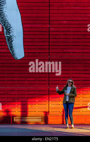 Eine junge Frau posiert für Fotos unter einem riesigen Cartoon Finger außerhalb der National Gallery, South Bank, London, England Stockfoto