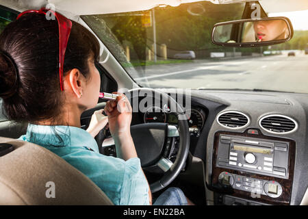 Frauen machen Lippen am Steuer des Autos Stockfoto