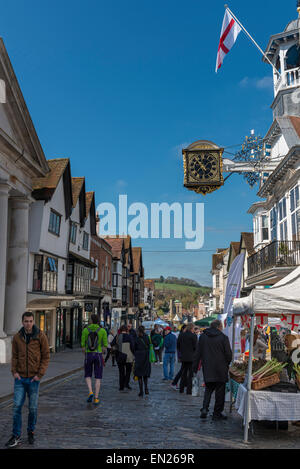 Regelmäßige monatliche Bauernmarkt auf der gepflasterten Guildford High Street mit der Guildhall-Uhr oben Stockfoto