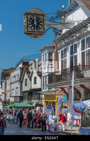 Regelmäßige monatliche Bauernmarkt auf der gepflasterten Guildford High Street mit der Guildhall-Uhr oben Stockfoto