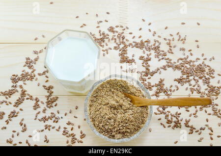 Leinsamen in der Schüssel und ein Glas Milch auf einem Tisch gedeckt mit Leinsamen Stockfoto