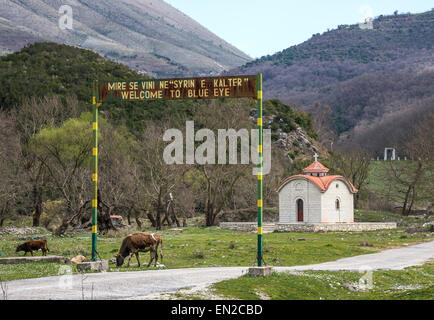 Willkommens-Schild am Eingang mit dem blauen Auge im Frühjahr in der Nähe von Delvine im Süden Albaniens. Stockfoto