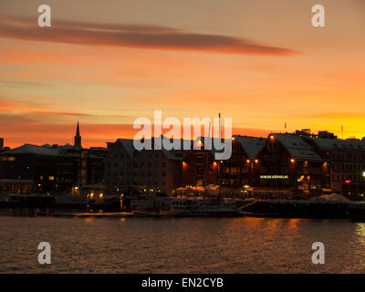 Sonnenuntergang hinter den Häusern in Tromsø mit einem orangefarbenen Himmel Stockfoto