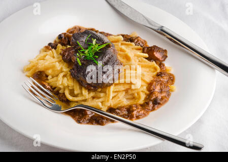 Langsam gekocht Schweinefleisch Wangen in Soße mit Spätzle Nudeln, Pilzen und frischen Kräutern. Stockfoto