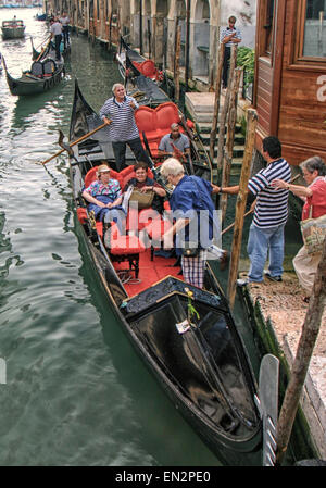 Venedig, Provinz Venedig, Italien. 7. Oktober 2004. Ein Gondoliere unterstützt ein Tourist in eine Gondel zu ihren anderen Touristen in einer altehrwürdigen venezianischen Tradition verbinden. Ein UNESCO-Weltkulturerbe, Venedig zählt zu den beliebtesten internationalen Reisezielen. © Arnold Drapkin/ZUMA Draht/Alamy Live-Nachrichten Stockfoto