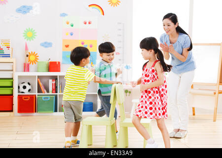 Die Kindergärtnerinnen und Kinder spielen Stockfoto