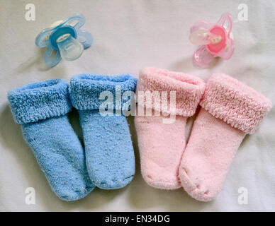 Rosa und blaue Socken und passende Schnuller liegen in einem Babybett in Frankfurt (Oder), Deutschland, 14. April 2015. Foto: Patrick Pleul/dpa Stockfoto