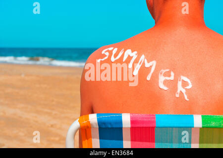 das Wort Sommer mit Sonnencreme auf den sonnenverbrannten Rückseite eines Mannes geschrieben ist, die am Strand Sonnenbaden Stockfoto