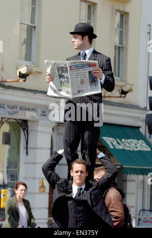 Duo Akrobaten, die ihr Handeln führen Sie die englischen Herren nahmen Mitglieder der Öffentlichkeit durch die Überraschung, als sie für einen Spaziergang in der Nähe des Spiegeltent auf der alten Steine in Brighton abgebildeten Lesen der Zeitung The Times ging. Stockfoto