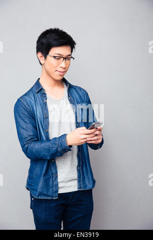 Asiatische glücklich mit Smartphone über grauen Hintergrund Stockfoto
