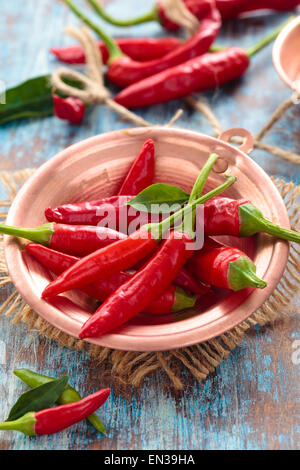 Mini rote hot Chilis in einem Kupfertopf. Auf blaue rustikalen Tisch. Stockfoto