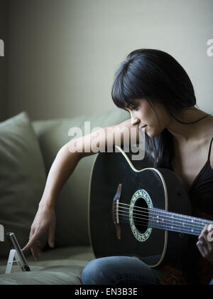 Frau tuning Gitarre mit Metronom Stockfoto