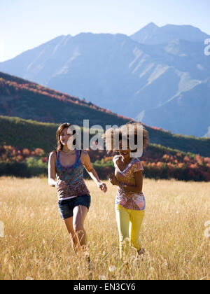 USA, Utah, South Fork, Mädchen (12-17) laufen auf Wiese, Berge im Hintergrund Stockfoto