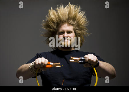 Mann mit verrückten Haaren halten Starthilfekabel Stockfoto