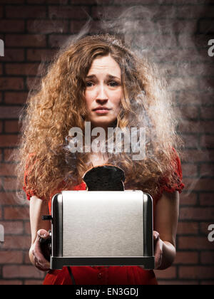 Frau hält einen Toaster mit einem verbrannten Stück toast Stockfoto