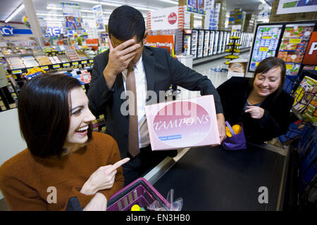 Mann an der Supermarkt Kasse mit Schachtel Tampons und zwei Frauen Stockfoto