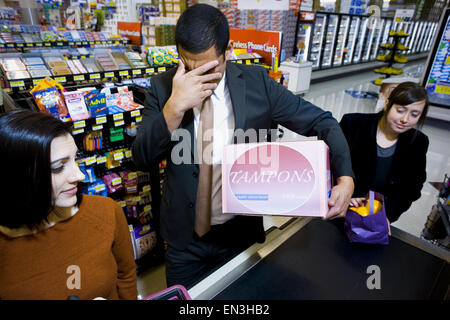 Mann an der Supermarkt Kasse mit Schachtel Tampons und zwei Frauen Stockfoto