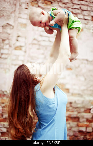 Schöne junge Frau mit Baby zu spielen. Glückliche Familie. Instagram-wie Vintage-Effekt. Stockfoto