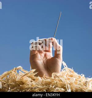 Hand mit einer Nadel im Heuhaufen Stockfoto