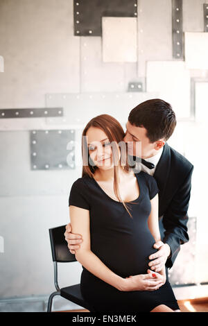 Mann küsst und umarmt seine schwangere Frau. Schönes und elegantes paar. Junge Familie. Stockfoto