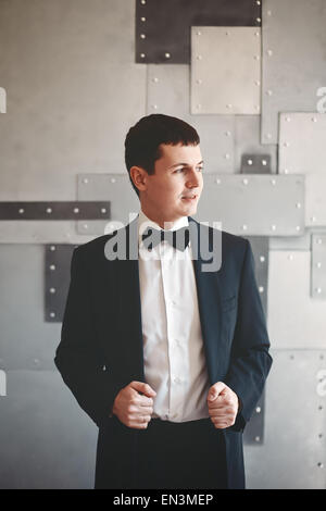 Eleganter jungen Mann im Smoking, die Hand in seine Hand auf Jacke lachen. Stockfoto