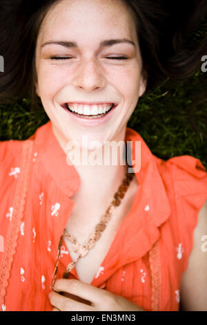Frau liegt auf dem Rasen vor Lachen Stockfoto